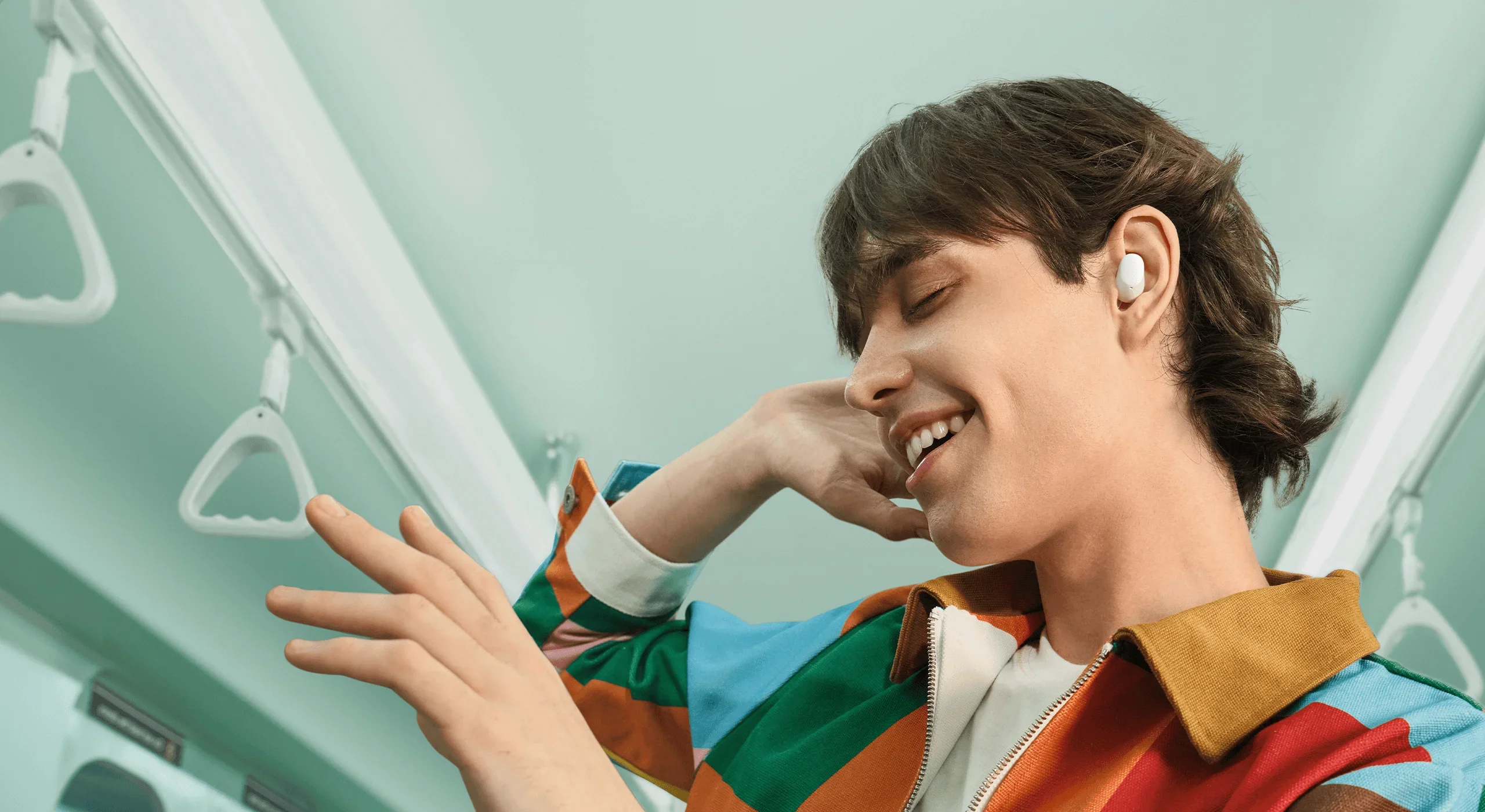 Jovem sorrindo no transporte público usando Redmi Buds 6 Play branco enquanto ouve música