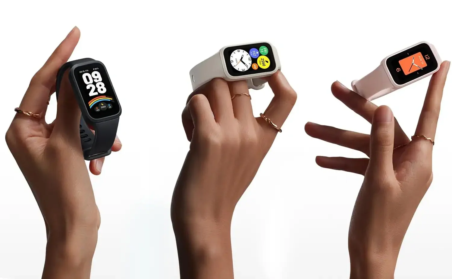 Três mãos segurando smartbands em cores diferentes — preta, branca e rosa — sobre um fundo branco, destacando as pulseiras e os mostradores digitais coloridos.
