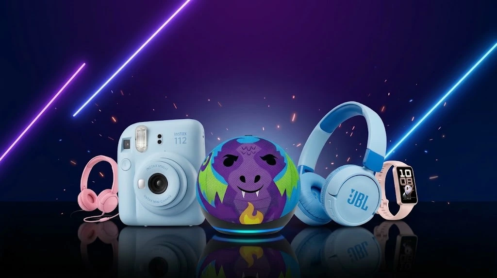 Camera instantanea azul, caixa de som preta com anel de luz, fones infantis e pulseira rosa sobre superficie reflexiva escura com luzes neon
